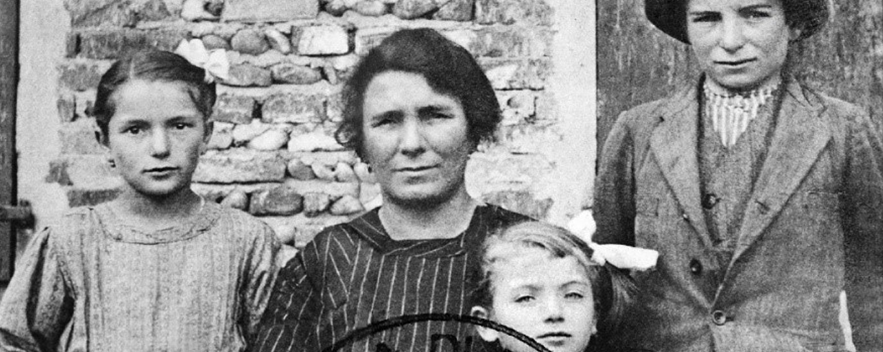 Três crianças e uma mulher posam para fotografia que está em preto e branco